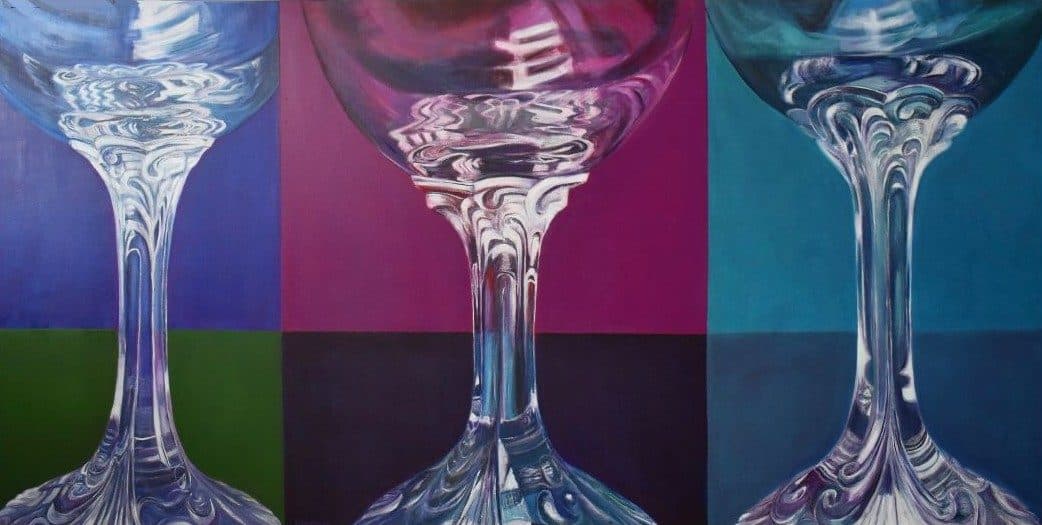 Three clear crystal wine glasses with ornate stems against colorful pop art backgrounds in blue, magenta, and teal